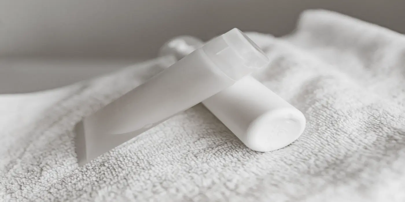 Moisturizer tube and sunscreen bottle resting on a white towel, moisturizer or sunscreen do you need both
